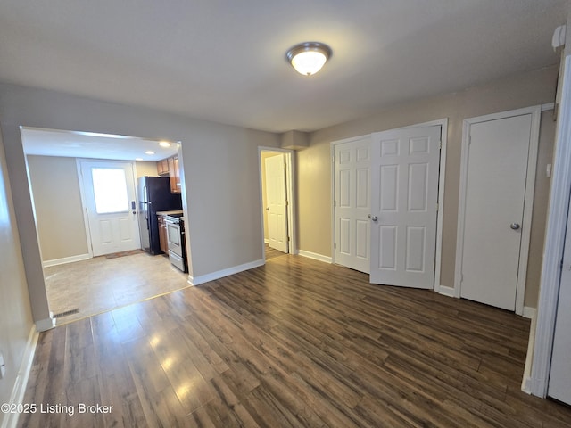 unfurnished living room with wood finished floors, visible vents, and baseboards