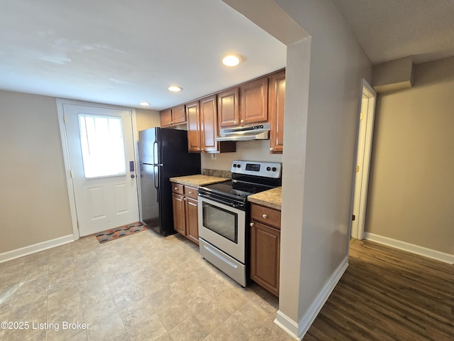 kitchen with recessed lighting, under cabinet range hood, baseboards, freestanding refrigerator, and stainless steel range with electric stovetop