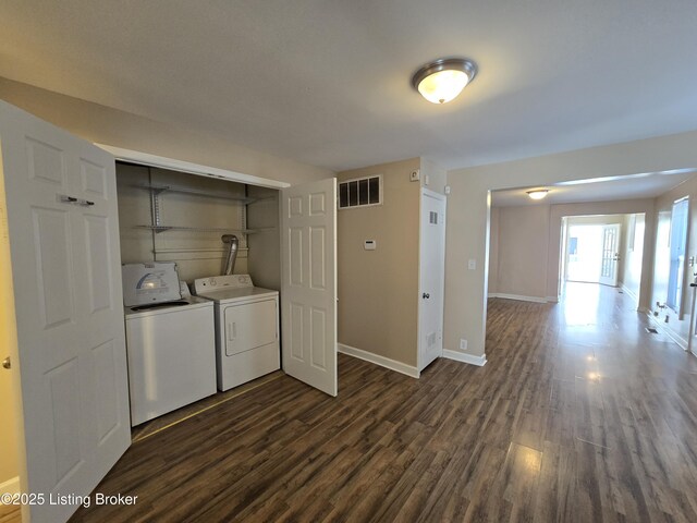 clothes washing area featuring laundry area, baseboards, visible vents, dark wood-type flooring, and washing machine and clothes dryer