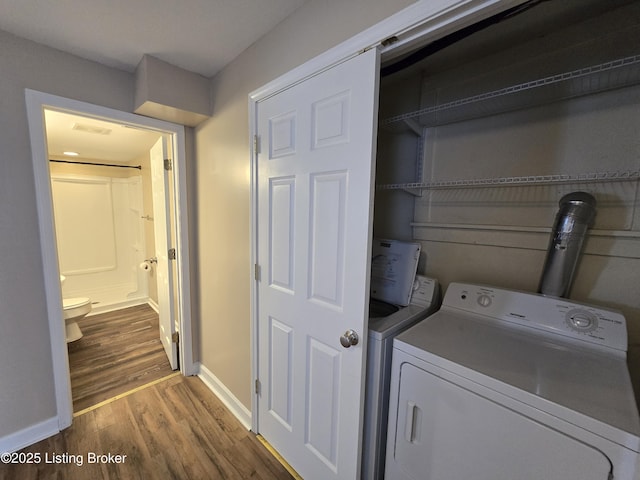 washroom featuring laundry area, washing machine and dryer, baseboards, and wood finished floors