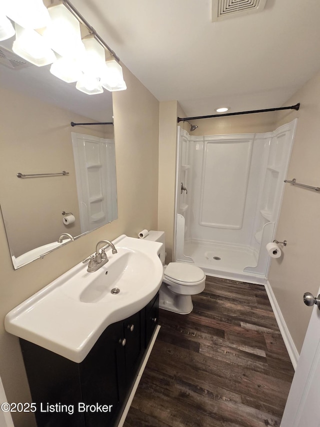 bathroom featuring visible vents, toilet, wood finished floors, walk in shower, and vanity