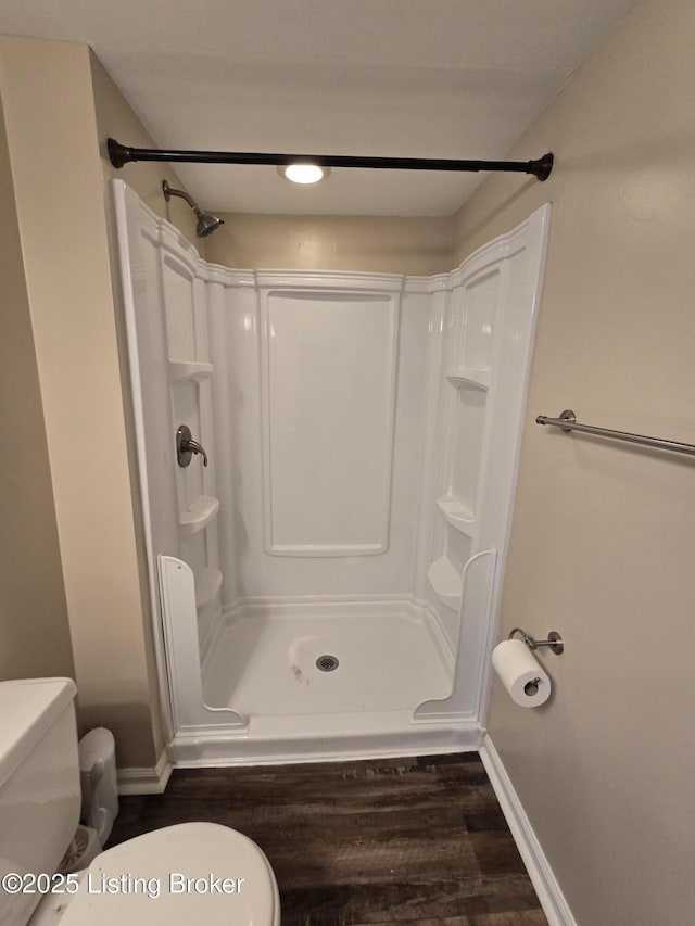 bathroom with baseboards, a shower stall, and toilet