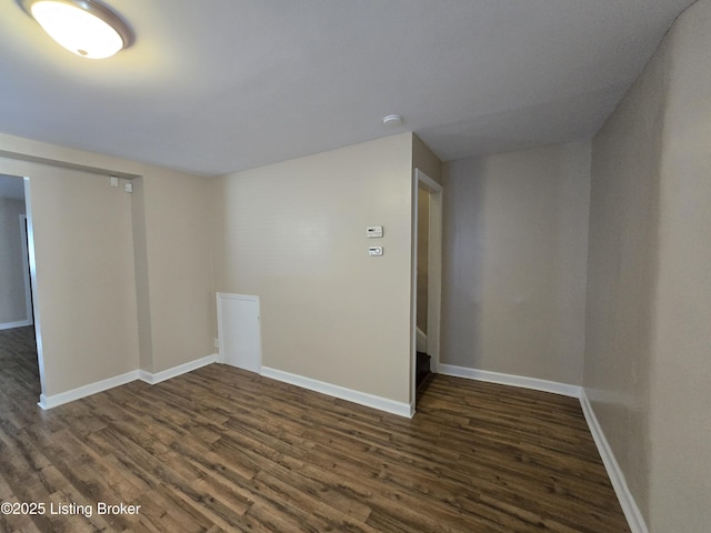 empty room with baseboards and dark wood finished floors