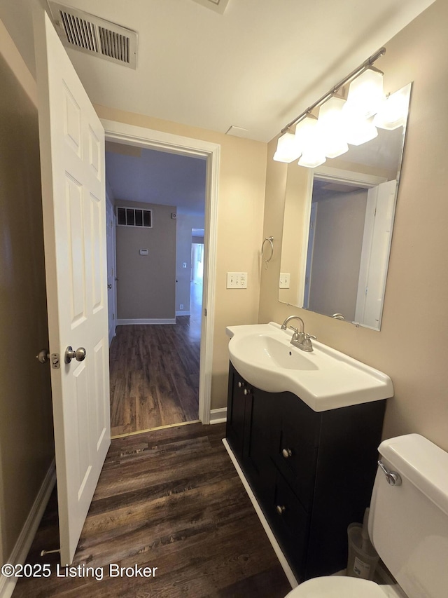 bathroom with toilet, visible vents, wood finished floors, and vanity