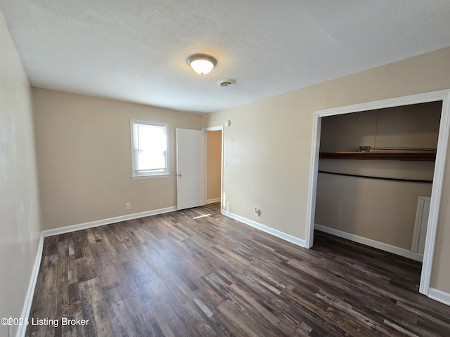 unfurnished bedroom with dark wood-style floors, a textured ceiling, visible vents, and baseboards