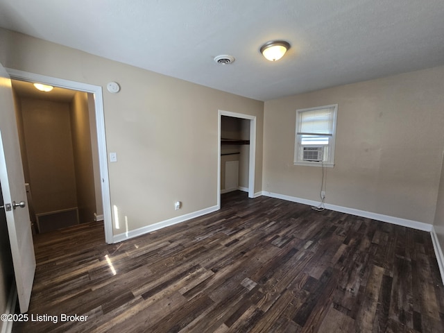 unfurnished bedroom with dark wood-type flooring, a closet, visible vents, and baseboards