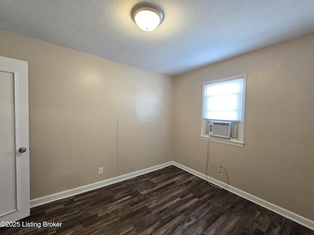 spare room featuring a textured ceiling, cooling unit, dark wood finished floors, and baseboards