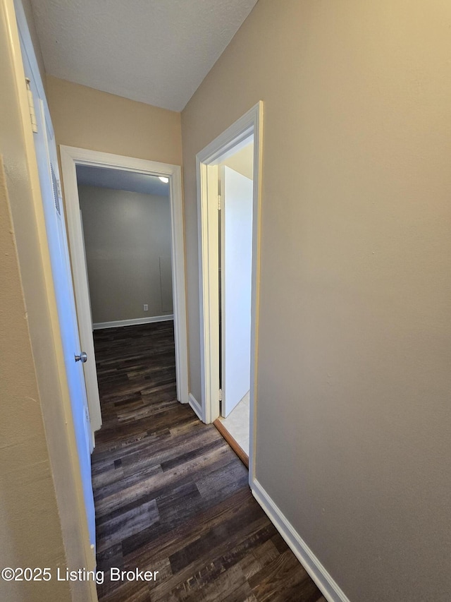 hallway featuring dark wood-style floors and baseboards