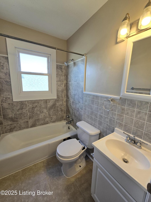 full bath featuring toilet, vanity, tile walls, tub / shower combination, and tile patterned floors