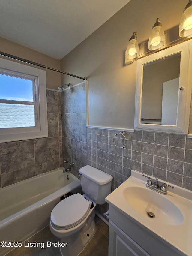 full bath with toilet, shower / bathtub combination, vanity, and tile walls