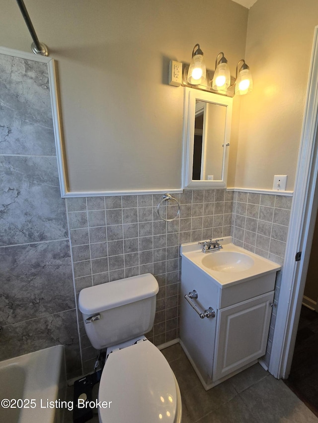 full bathroom featuring tile patterned flooring, toilet, vanity, tile walls, and wainscoting