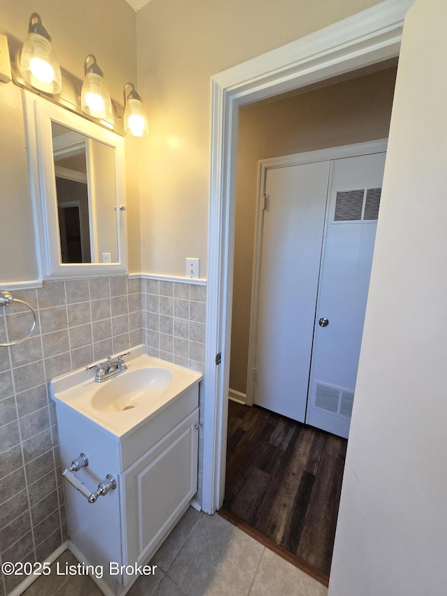 bathroom featuring tile patterned flooring, visible vents, tile walls, and vanity