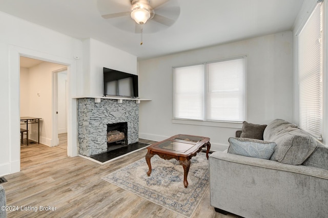 living room featuring ceiling fan, hardwood / wood-style floors, and a fireplace