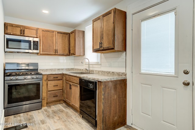 kitchen with decorative backsplash, sink, stainless steel appliances, and light wood-type flooring