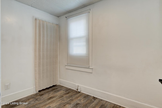 empty room featuring a paneled ceiling and dark hardwood / wood-style flooring