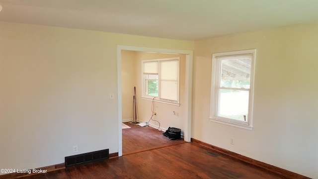 empty room featuring a healthy amount of sunlight and dark wood-type flooring