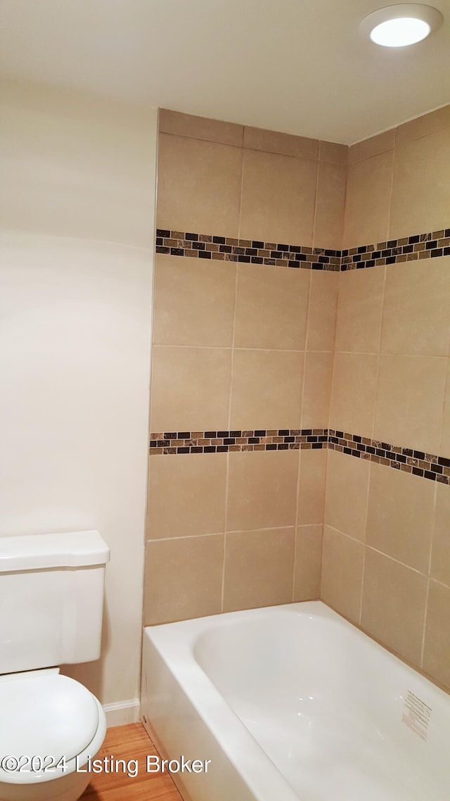 bathroom with toilet and tiled shower / bath