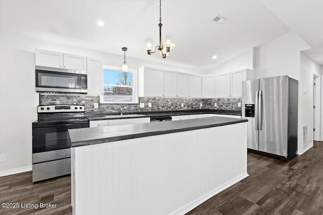 kitchen with lofted ceiling, sink, white cabinetry, hanging light fixtures, and stainless steel appliances