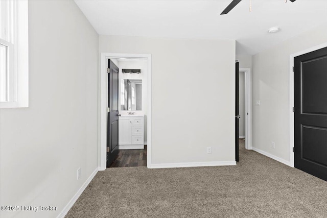 unfurnished bedroom with dark colored carpet, ceiling fan, and ensuite bathroom