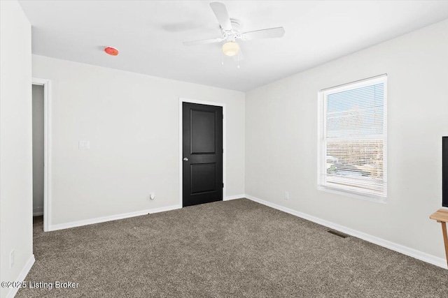 unfurnished room featuring dark colored carpet and ceiling fan