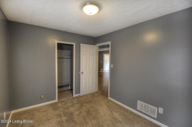 unfurnished bedroom featuring a closet, a textured ceiling, and carpet floors