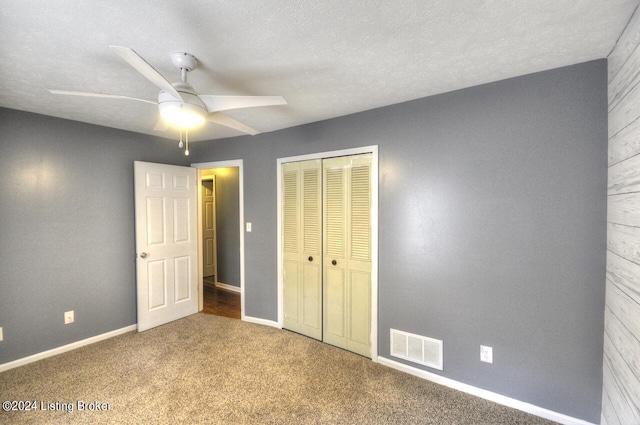 unfurnished bedroom with ceiling fan, a textured ceiling, a closet, and carpet flooring