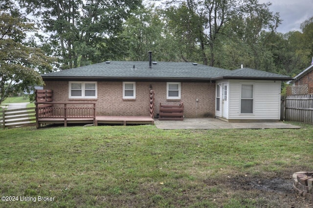 rear view of house with a patio, a wooden deck, and a yard