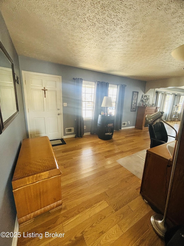 foyer entrance with light hardwood / wood-style floors and a textured ceiling