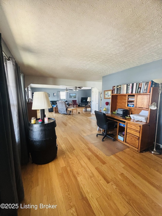 home office featuring wood-type flooring, a textured ceiling, and ceiling fan