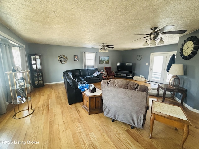 living room with ceiling fan, a textured ceiling, and light hardwood / wood-style flooring