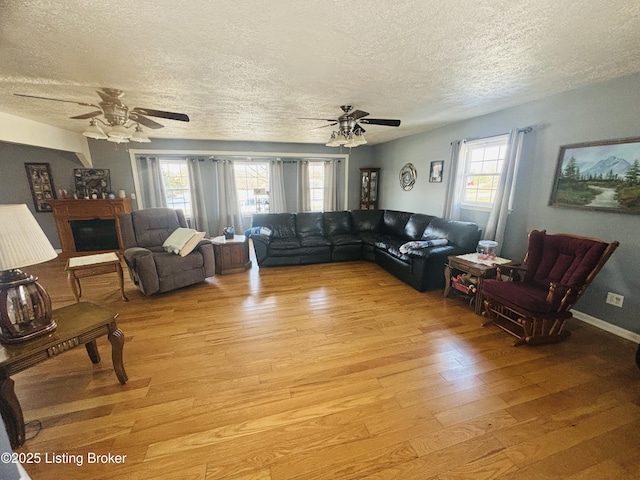 living room featuring ceiling fan, a textured ceiling, a wealth of natural light, and light wood-type flooring