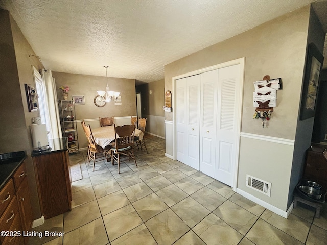 dining space featuring a textured ceiling, light tile patterned floors, and a notable chandelier