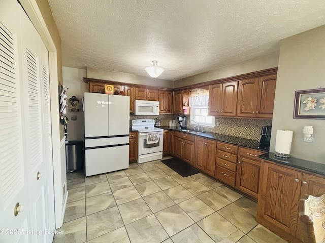 kitchen with sink, tasteful backsplash, light tile patterned floors, white appliances, and a textured ceiling