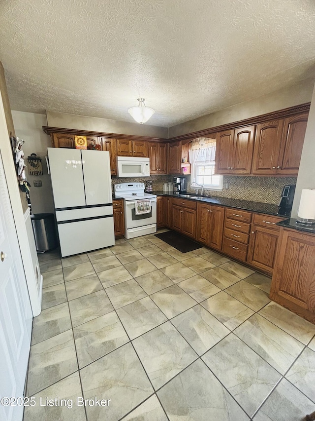 kitchen with sink, white appliances, and a textured ceiling