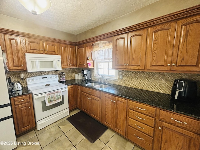 kitchen featuring sink, tasteful backsplash, dark stone counters, light tile patterned flooring, and white appliances