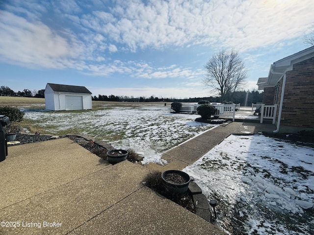 yard layered in snow featuring a patio area and a storage shed