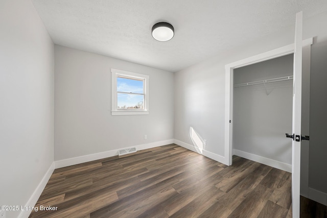 unfurnished bedroom featuring a closet, dark hardwood / wood-style floors, and a textured ceiling