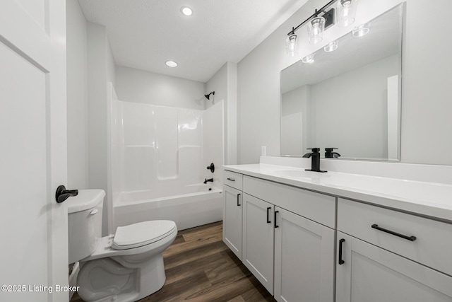 full bathroom with hardwood / wood-style flooring, a textured ceiling, toilet, vanity, and shower / bathtub combination