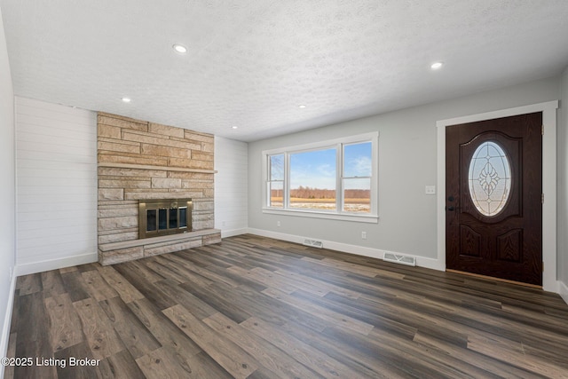 entryway featuring a textured ceiling, dark hardwood / wood-style flooring, and a fireplace