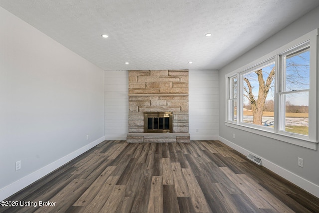 unfurnished living room with a fireplace, dark wood-type flooring, and a textured ceiling