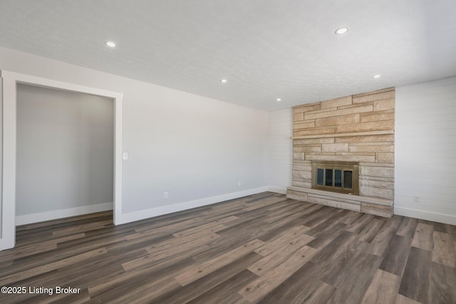 unfurnished living room featuring dark wood-type flooring and a stone fireplace