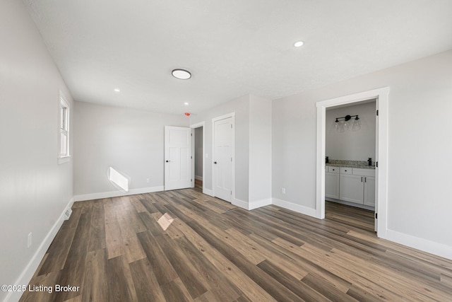 unfurnished bedroom with ensuite bathroom and dark hardwood / wood-style flooring