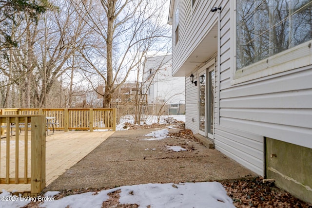 yard layered in snow with a patio and a wooden deck