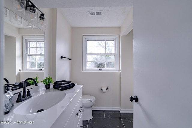 bathroom with toilet, a textured ceiling, a wealth of natural light, and vanity