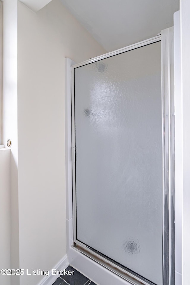 bathroom with an enclosed shower and tile patterned flooring