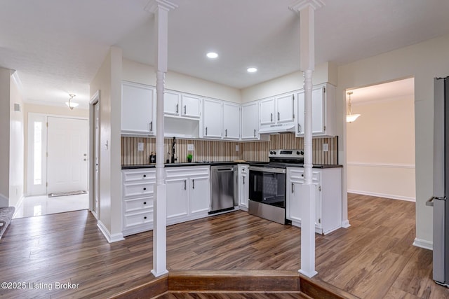 kitchen with appliances with stainless steel finishes, white cabinetry, sink, dark wood-type flooring, and backsplash