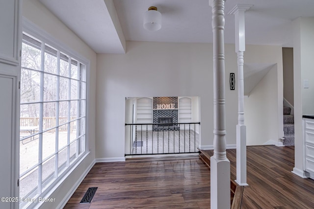 interior space with a brick fireplace and dark hardwood / wood-style flooring