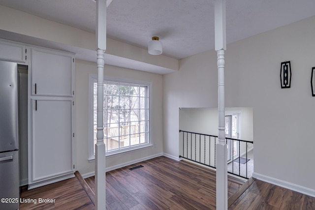 interior space with white cabinetry, dark hardwood / wood-style flooring, and stainless steel fridge