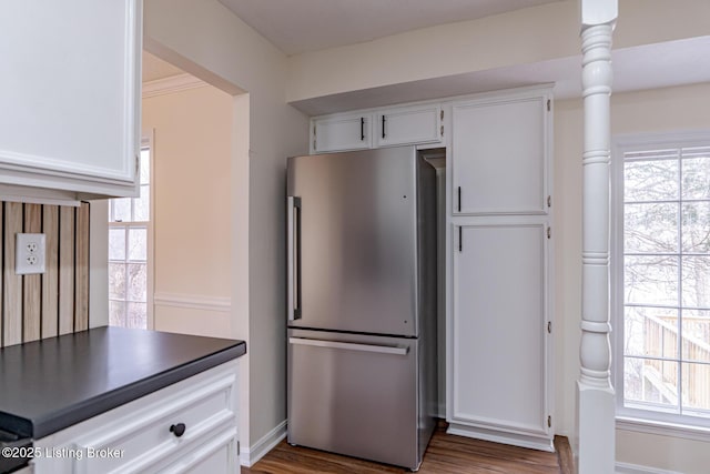 kitchen with dark wood-type flooring, white cabinetry, a healthy amount of sunlight, and stainless steel refrigerator