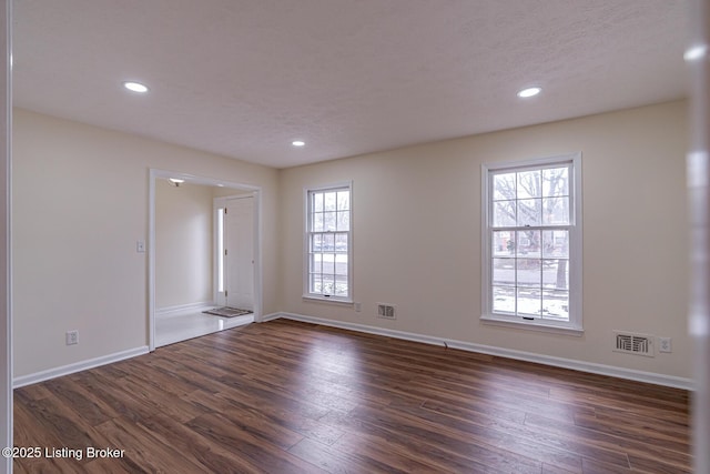 empty room featuring plenty of natural light and dark hardwood / wood-style flooring